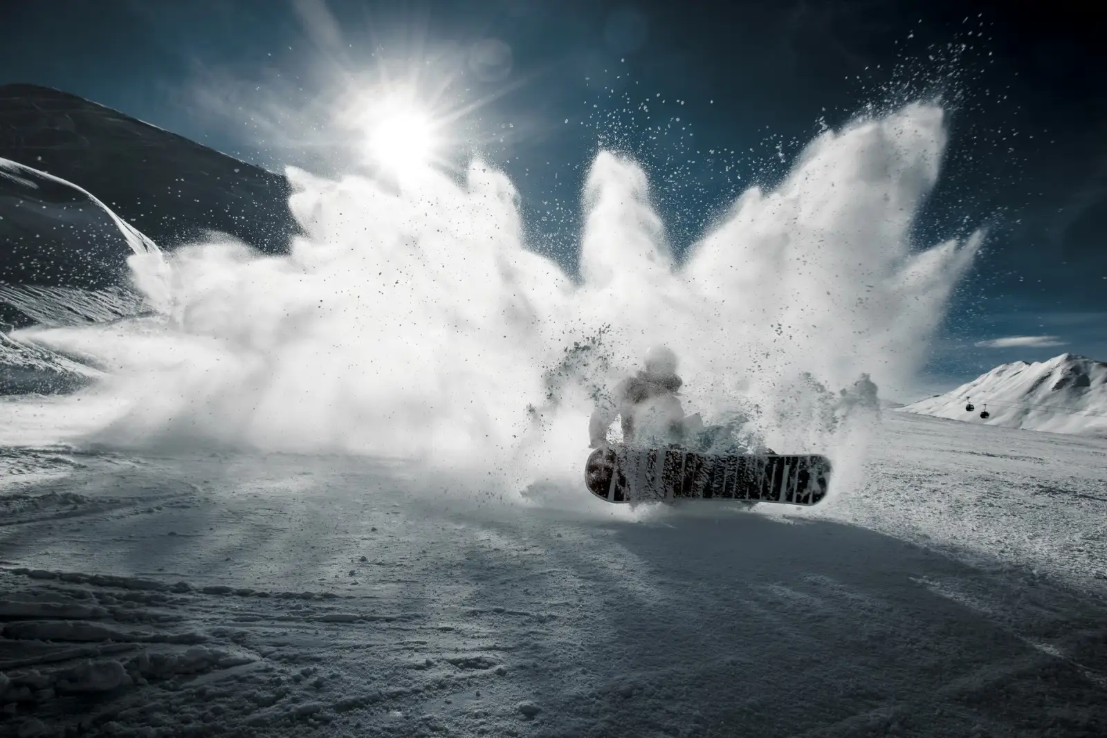 Người trượt snowboard làm tung bụi tuyết dưới nắng
